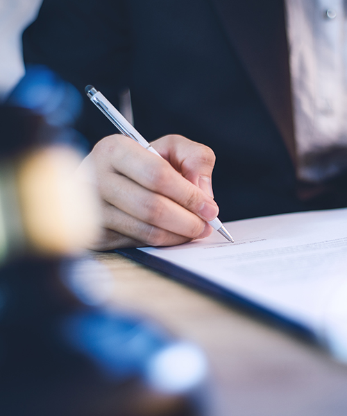 A business professional signing a contract with a pen on a document