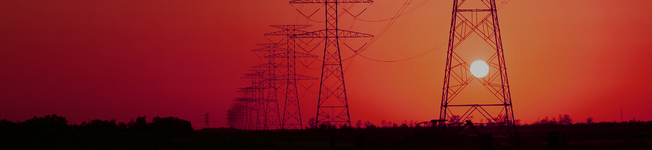 Silhouetted electricity pylons stand against a striking red sunset