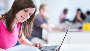 A woman working diligently at a table with her laptop