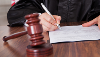 A judge, seated at a desk, signing a legal document