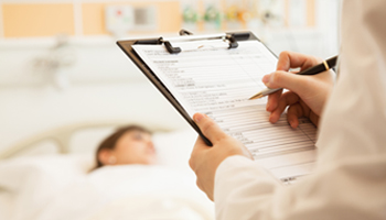 A doctor writes notes on a clipboard