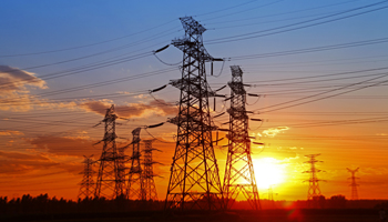 Electricity pylons stand tall against a colorful sunset